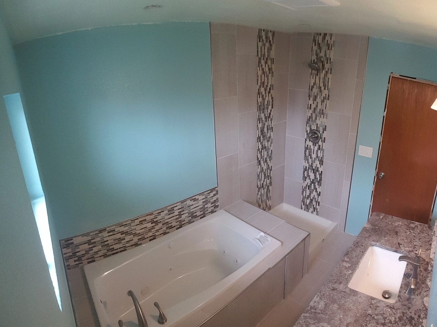 Soaking tub set into tile, with a mosaic band carried up the wall