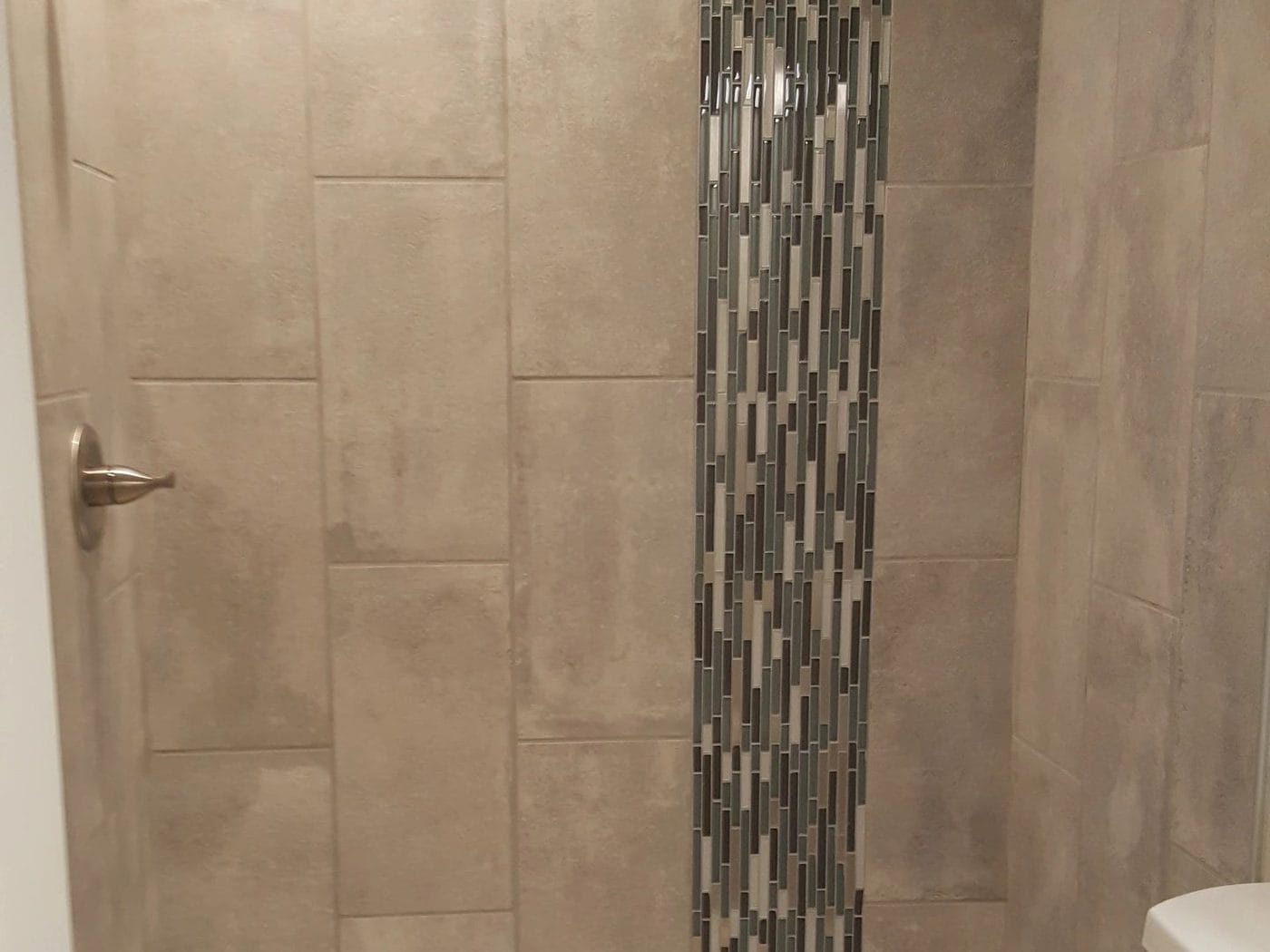 Tub and shower run together, with a vertical mosaic inlay